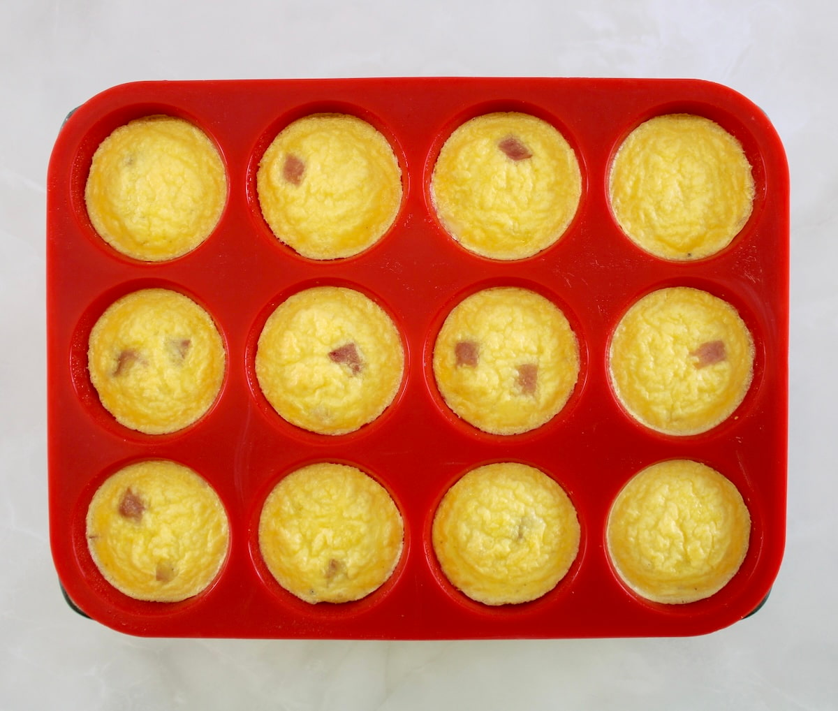 Cottage Cheese and Ham Egg Bites in red silicone muffin pan
