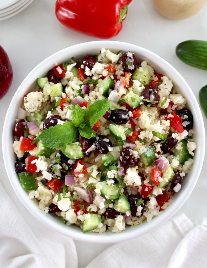 Greek Cauliflower Rice in white bowl with fresh mint garnish