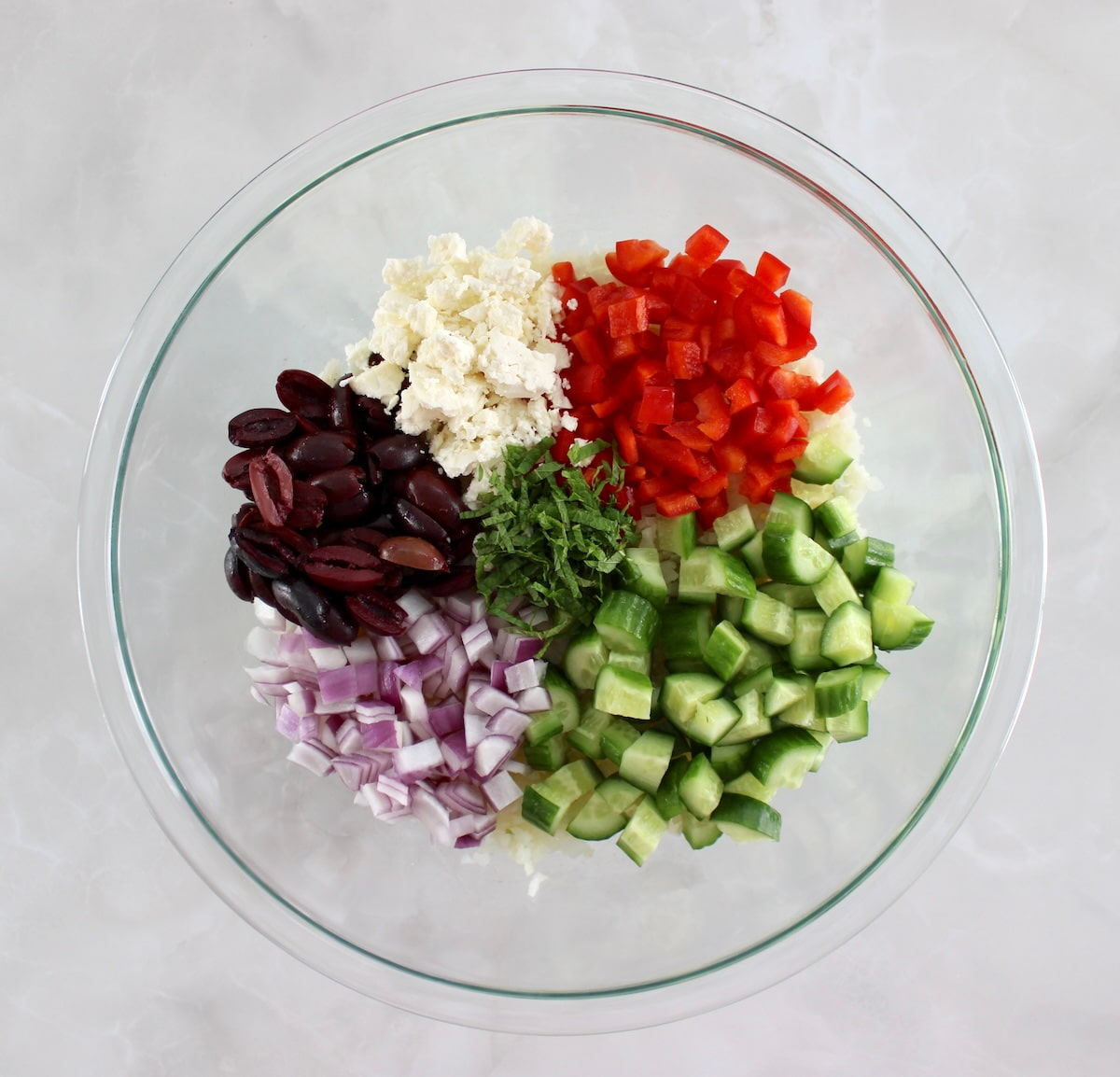 Greek Cauliflower Rice ingredients in glass bowl in sections