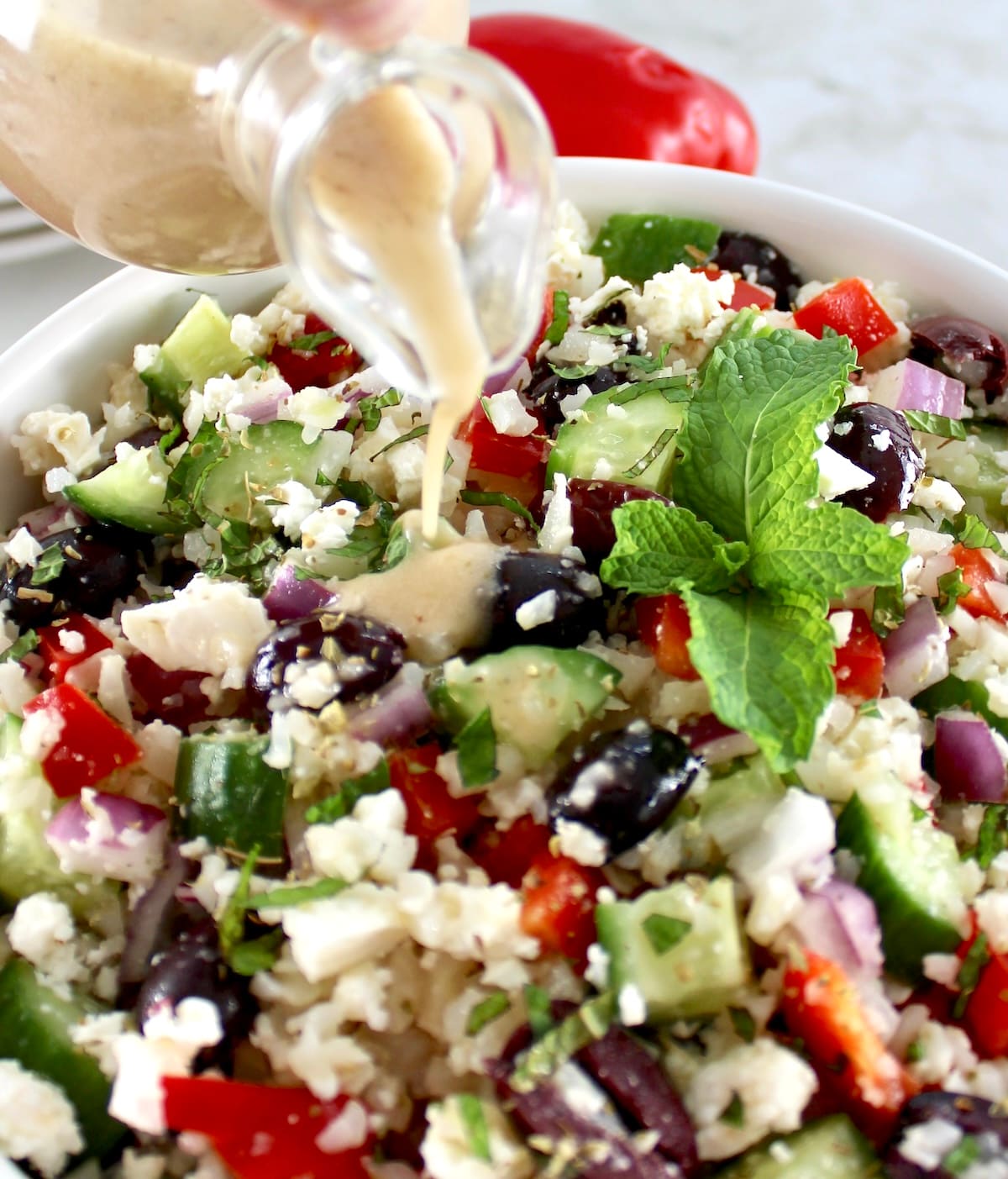 dressing being poured over Greek Cauliflower Rice