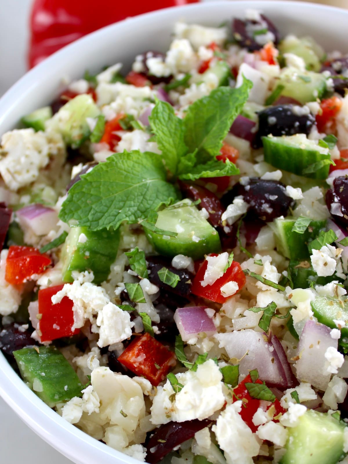 closeup of Greek Cauliflower Rice in white bowl with fresh mint on top