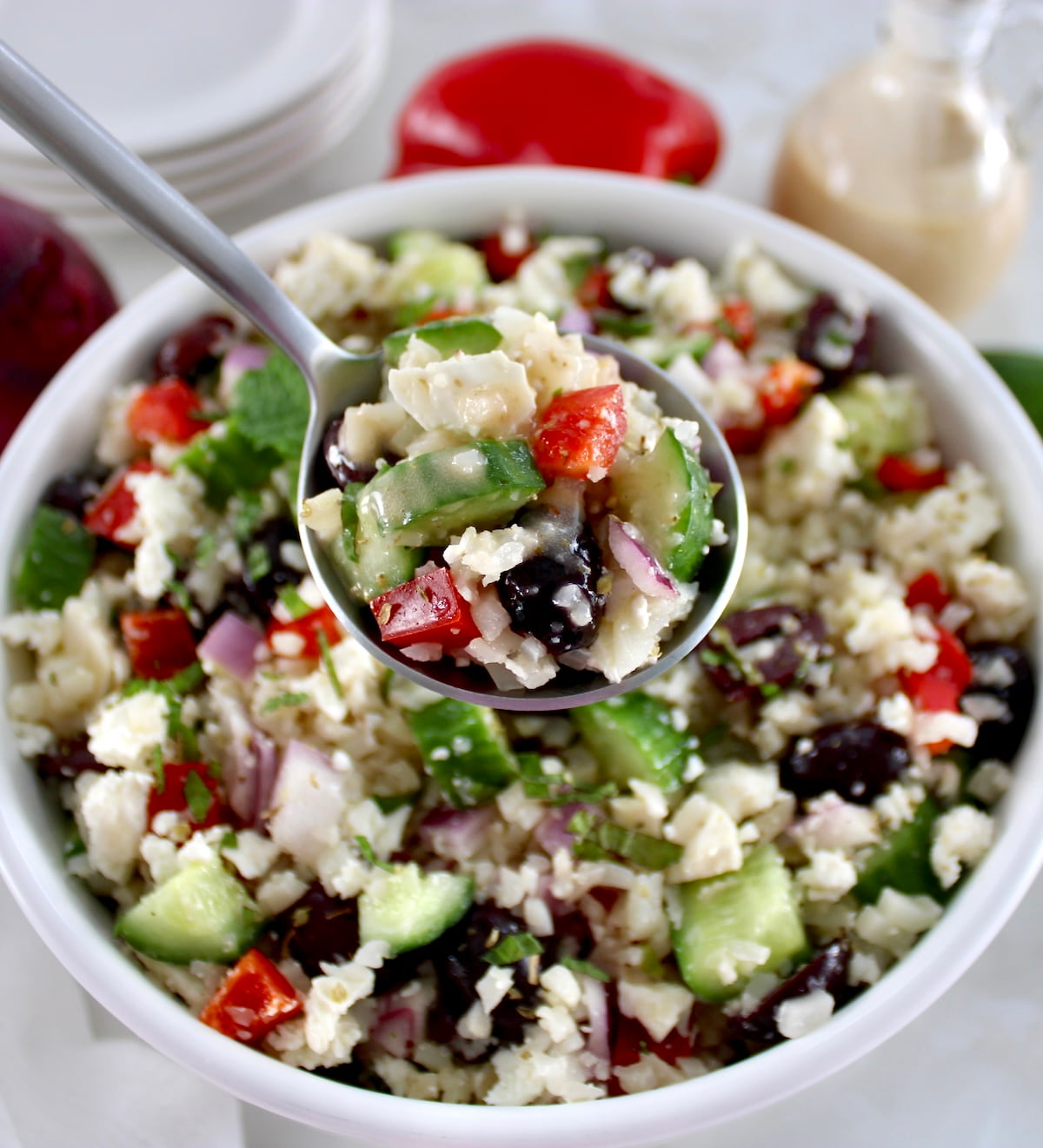 Greek Cauliflower Rice in spoon held up over white bowl