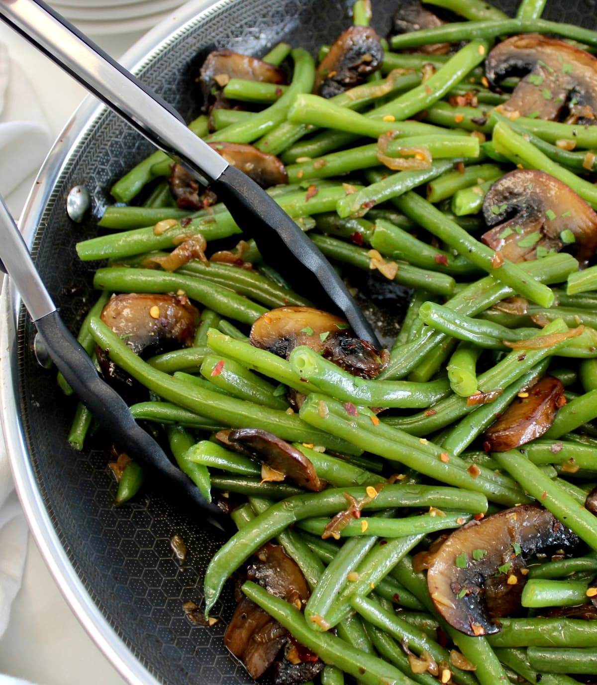 Green Beans with Mushrooms in skillet with black tongs on side