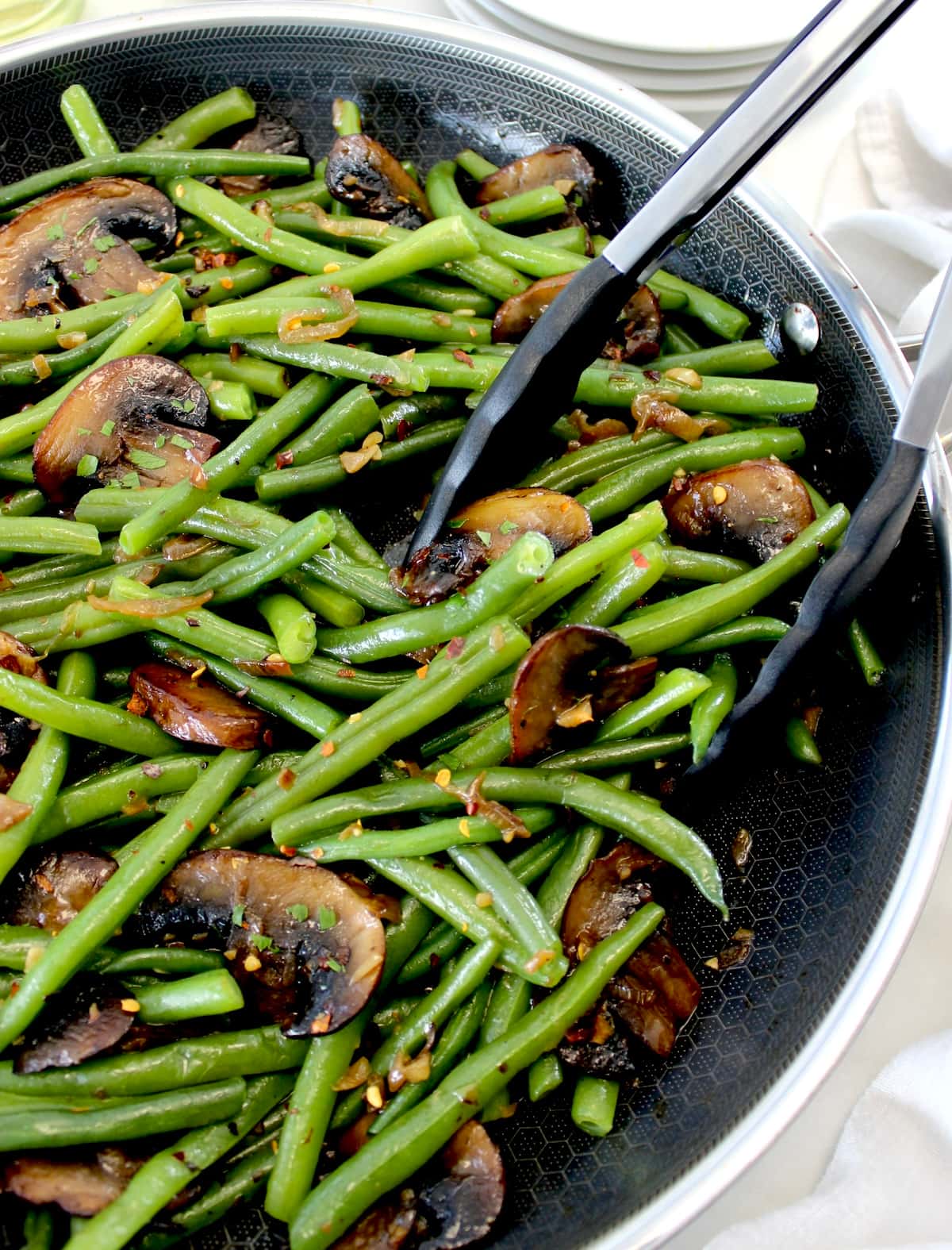 Green Beans with Mushrooms in skillet with black tongs on side
