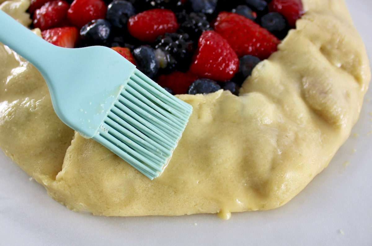 brushing egg wash on Keto Mixed Berry Galette crust
