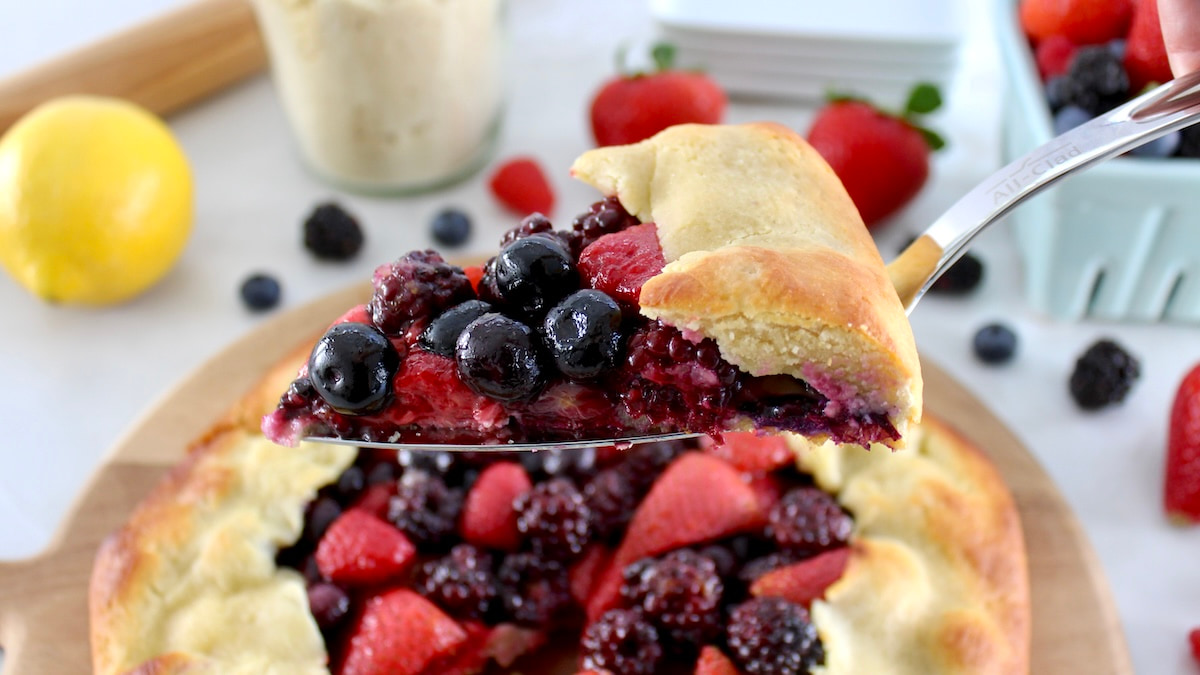 holding up slice of Keto Mixed Berry Galette