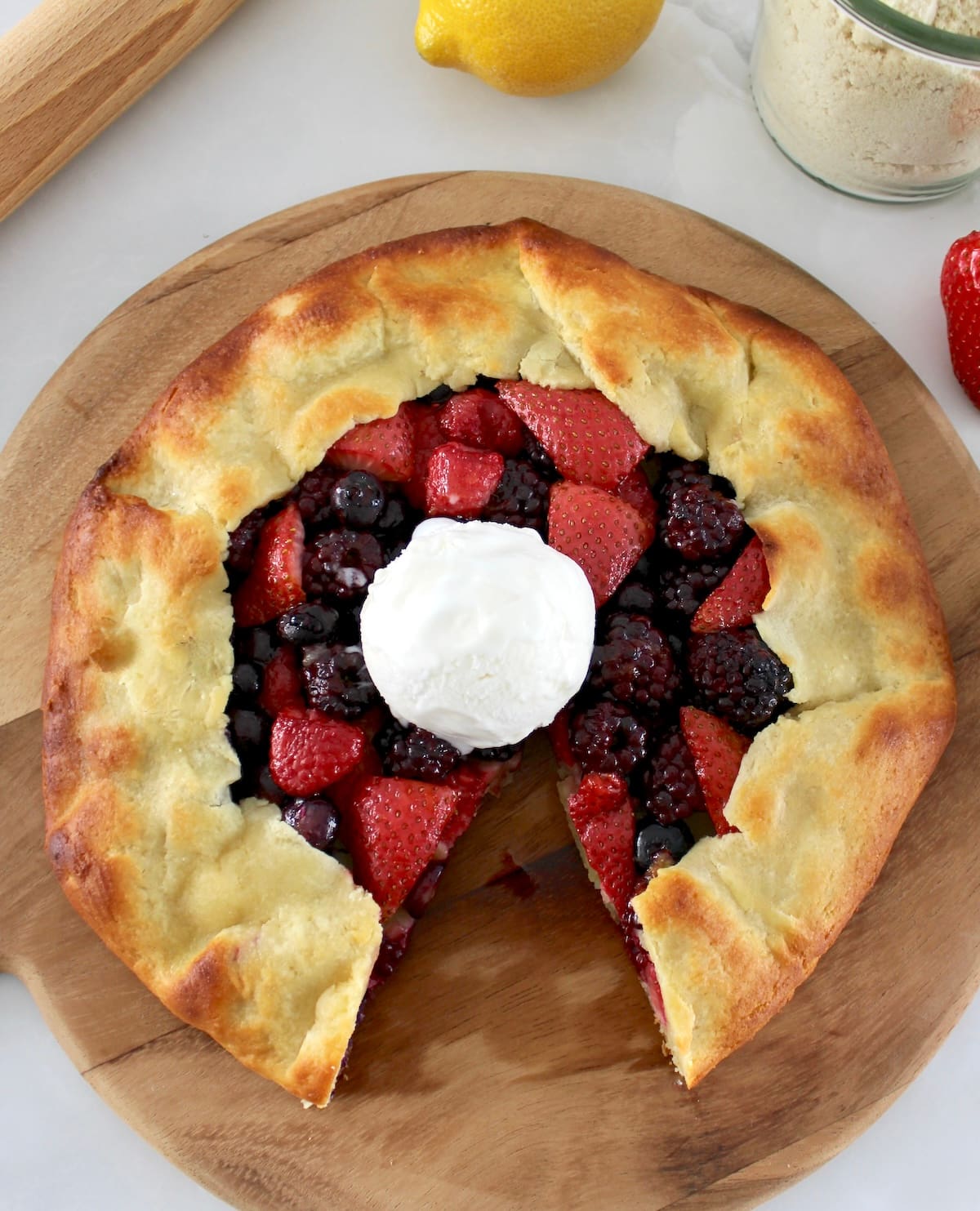 Keto Mixed Berry Galette with vanilla ice cream on top with slice missing