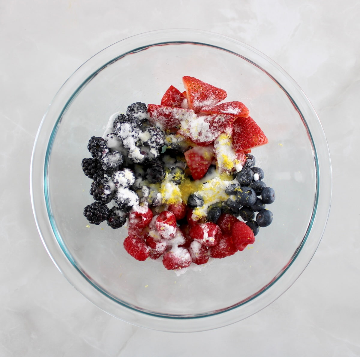frozen mixed berries with sweetener on top in glass bowl