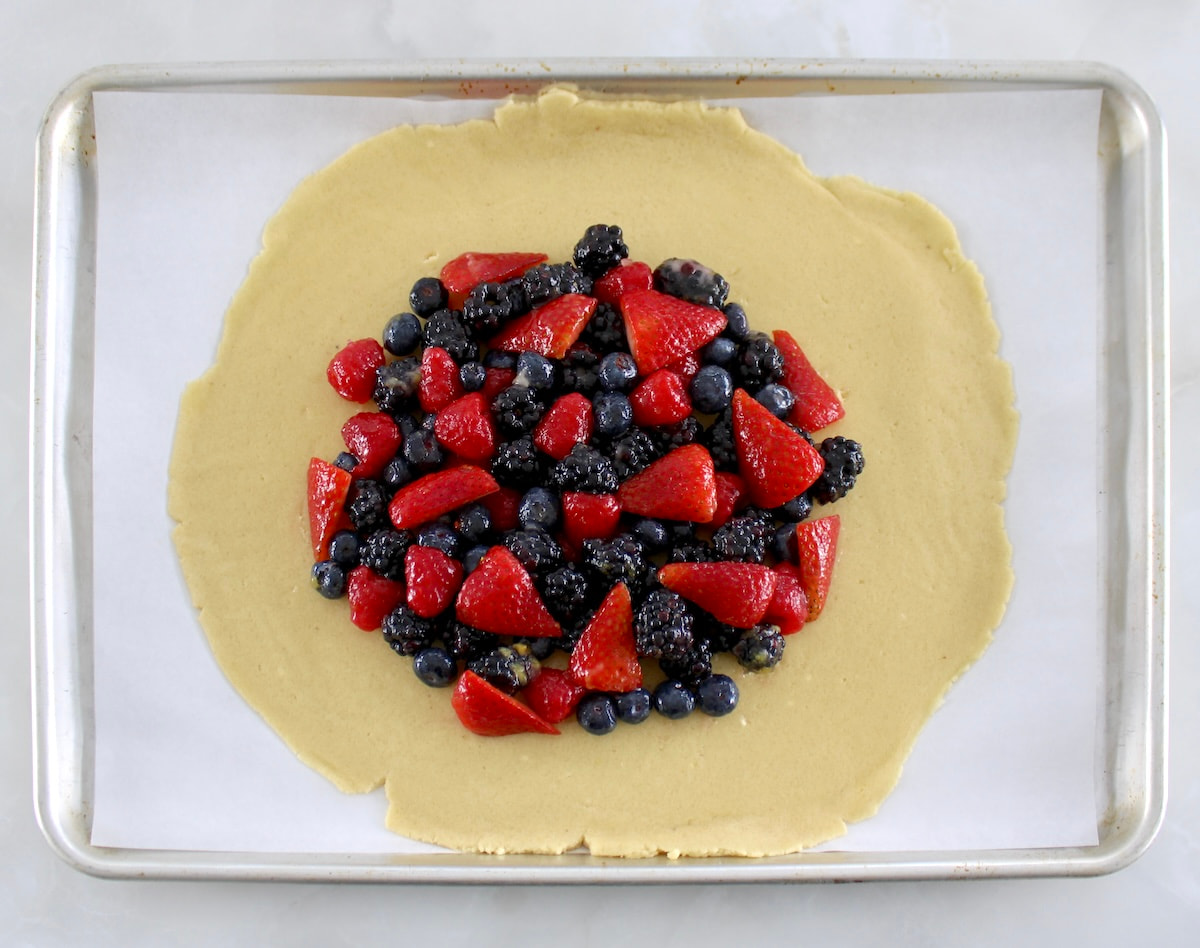 keto pie crust on parchment paper with mixed berries in center