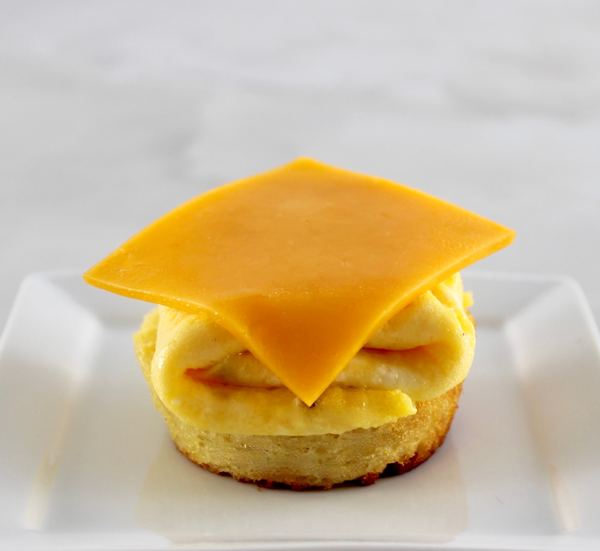 bottom half of biscuit with folded scramble eggs and slice of cheddar on top