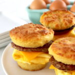 3 Keto Sausage Egg and Cheese Biscuits on white plate with eggs in back