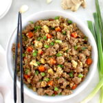 overhead view of Pork Fried Cauliflower Rice in white bowl with black chopsticks on side