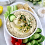 Roasted Garlic Cauliflower Hummus in white bowl with fresh veggies around