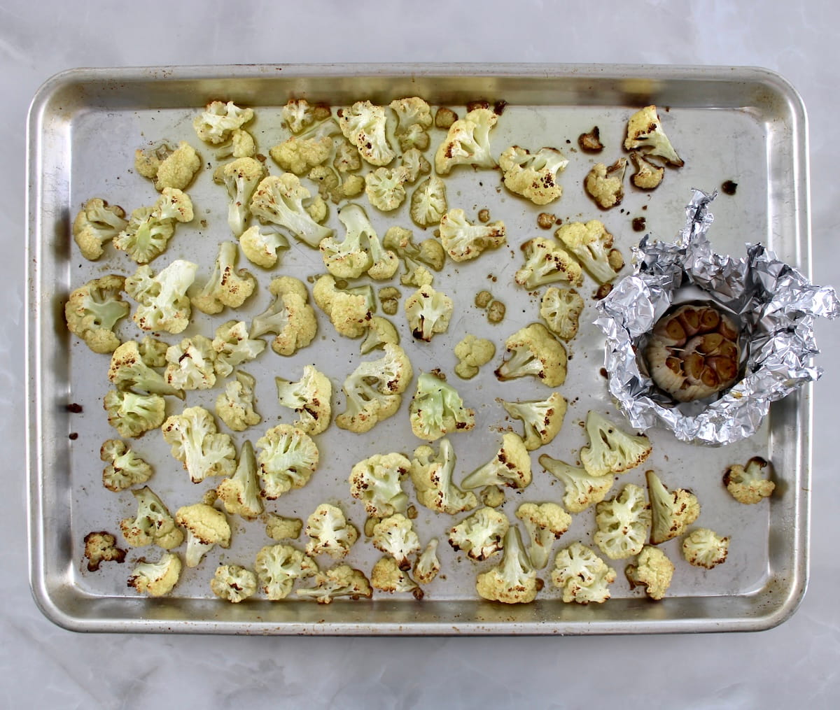 roasted cauliflower and garlic in foil on baking sheet