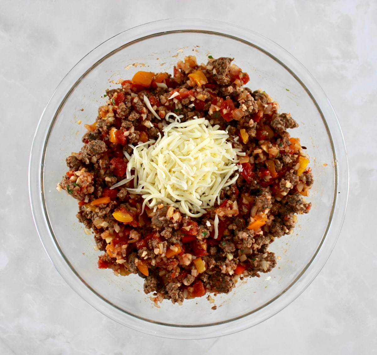 Stuffed Pepper Casserole ingredients in glass bowl with shredded mozzarella on top