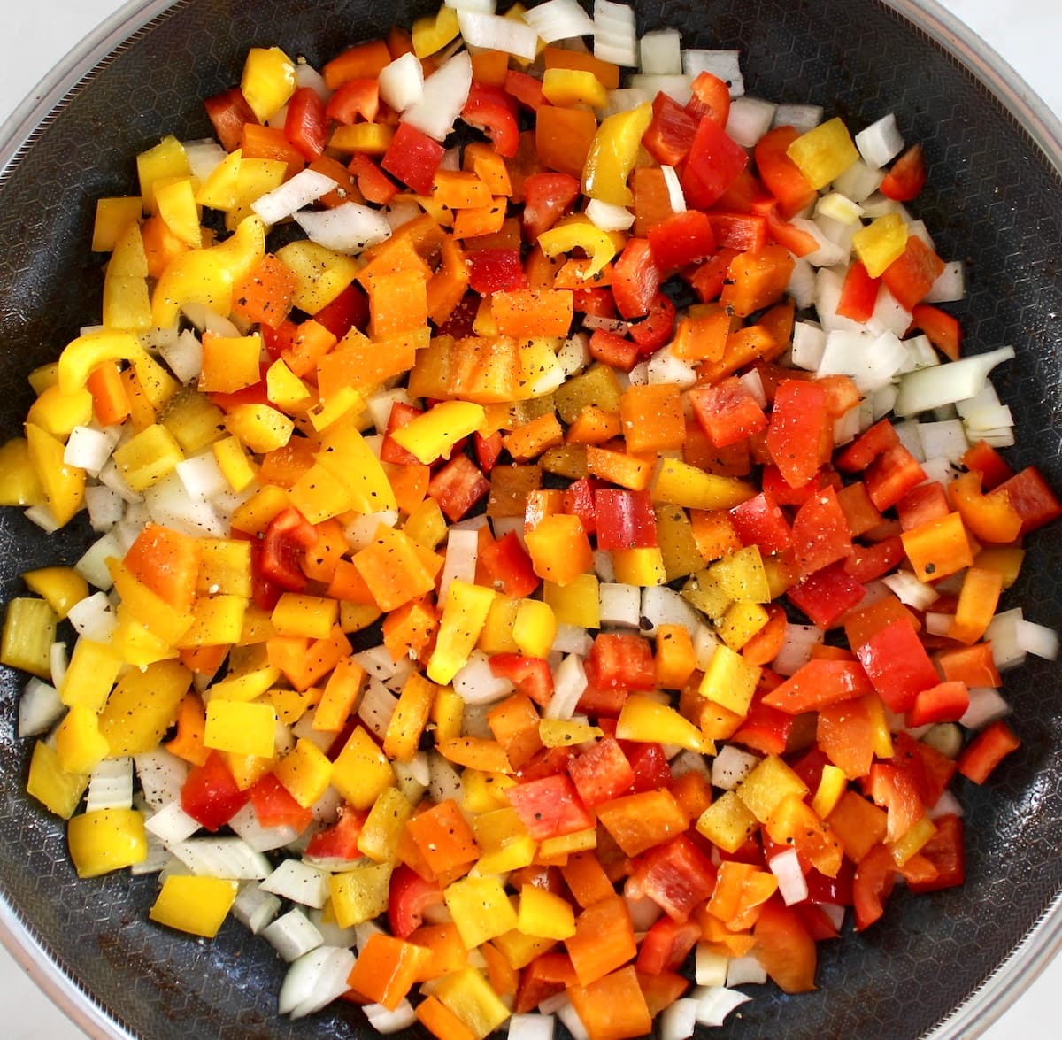diced bell peppers and onions in skillet