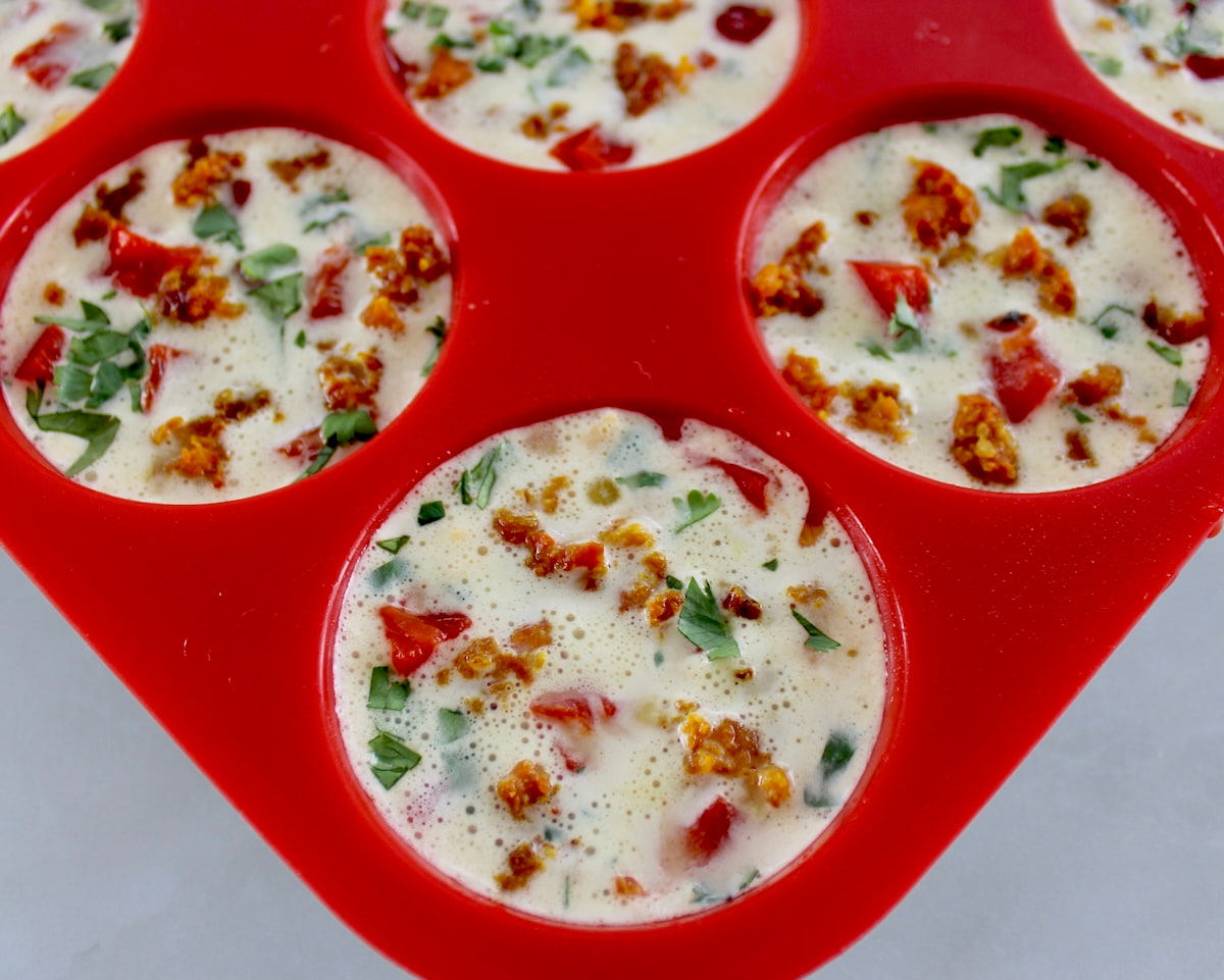 Chorizo and Pepper Egg Muffins in red muffin pan unbaked