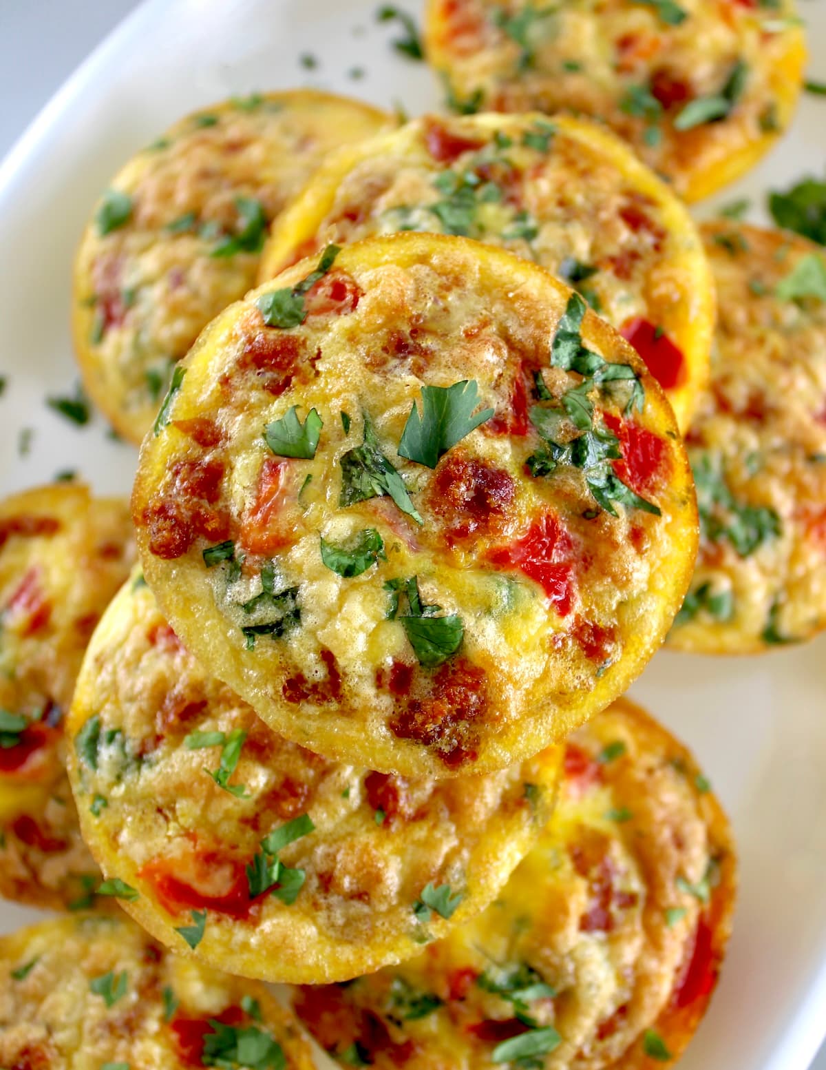 overhead view of Chorizo and Pepper Egg Muffins stacked up on white plate