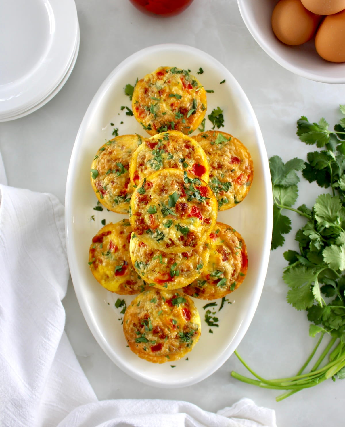 overhead view of Chorizo and Pepper Egg Muffins stacked up on white oval platter