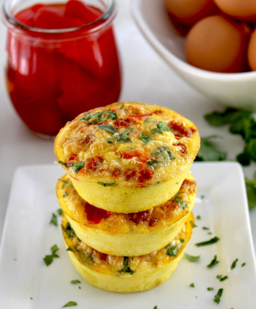 3 Chorizo and Pepper Egg Muffins stacked up on white plate with chopped cilantro