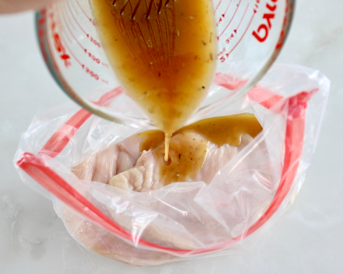 marinade being poured over chicken in food storage bag