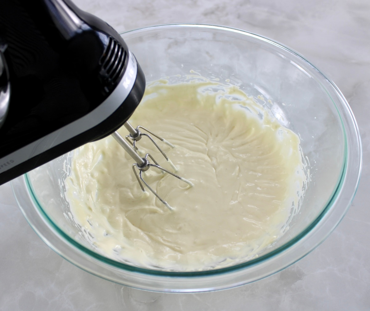 keto cheesecake batter in glass bowl with hand mixer