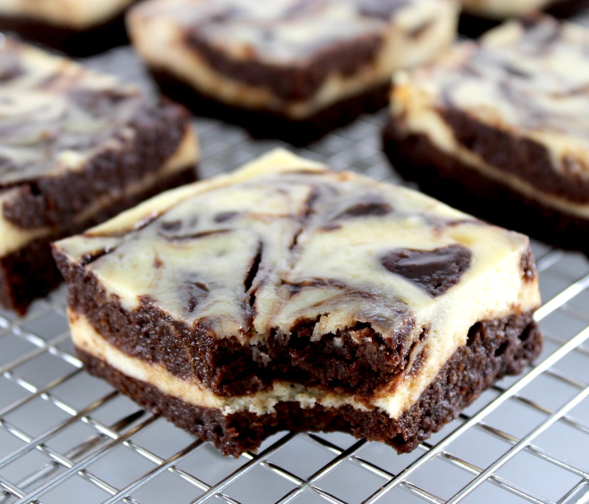 closeup of Keto Cheesecake Brownie Bars on cooling rack with bite missing
