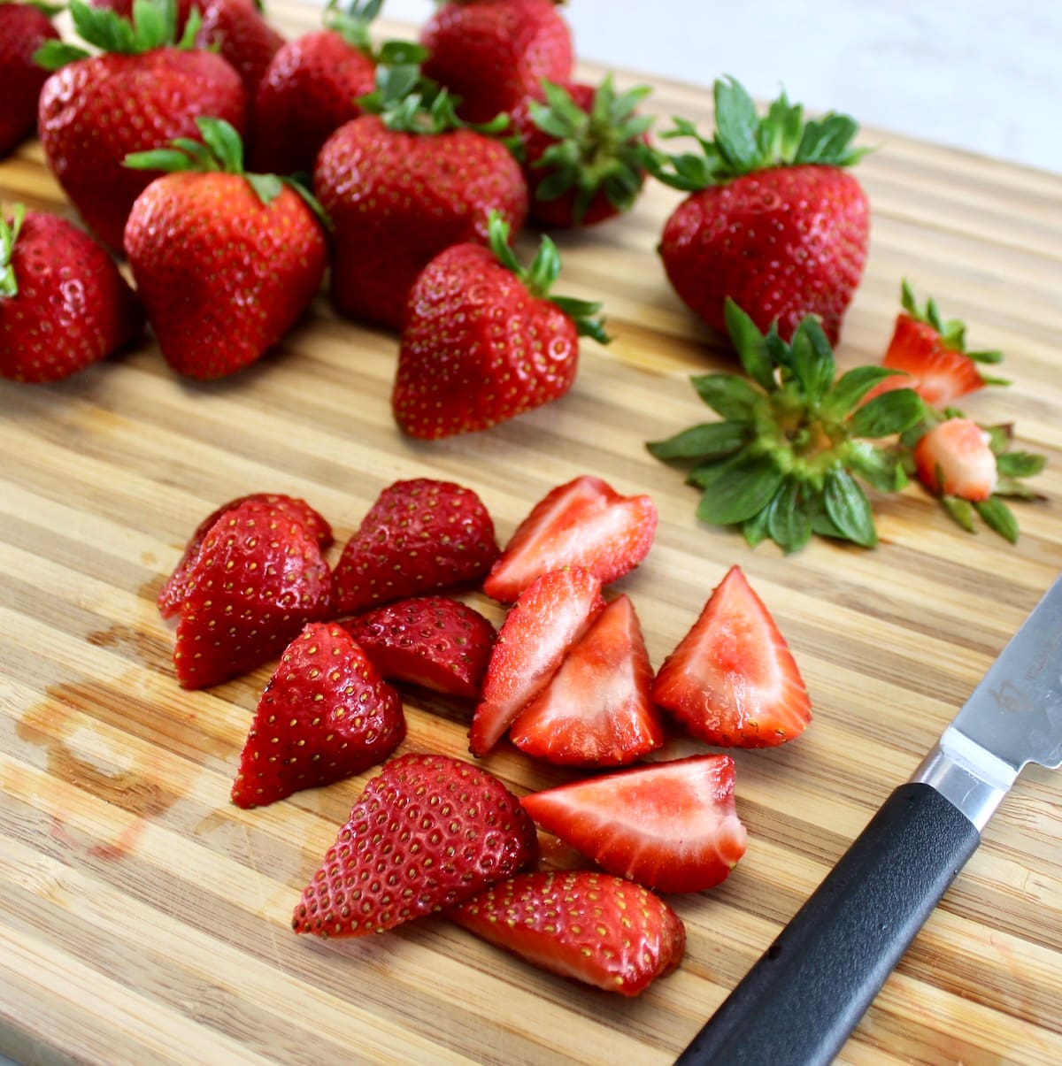 cut up strawberries on cutting board with paring knife
