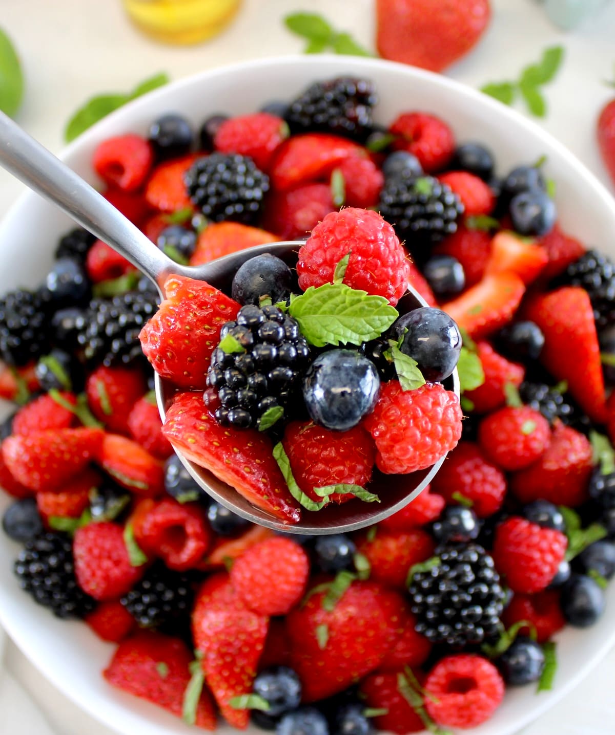 Keto Fruit Salad in spoon held up over white bowl