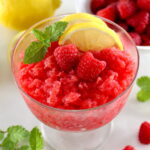 Raspberry Lemon Granita in glass with lemon slices, 2 raspberries and fresh mint on top