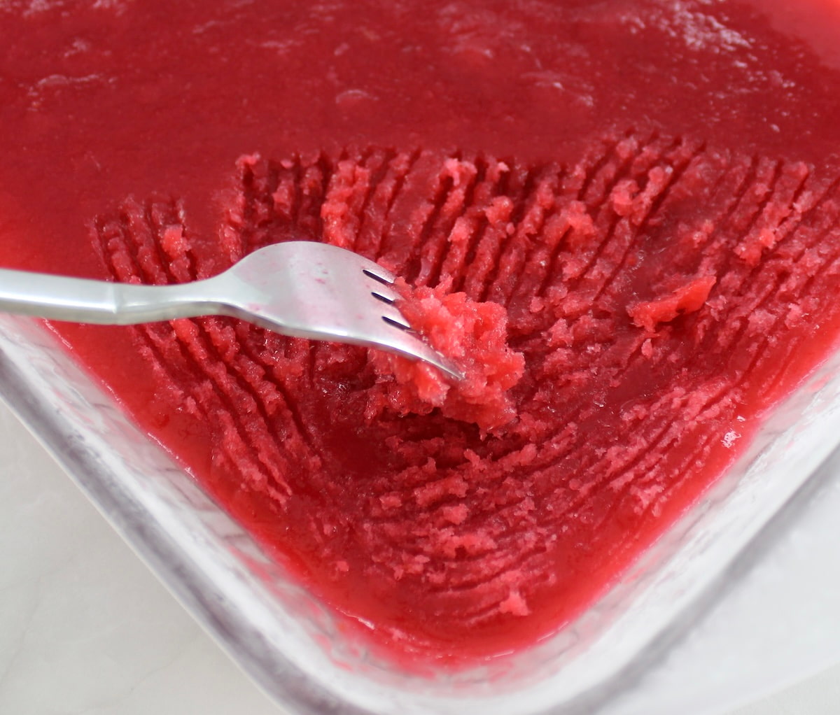 fork scraping Raspberry Lemon Granita in glass dish