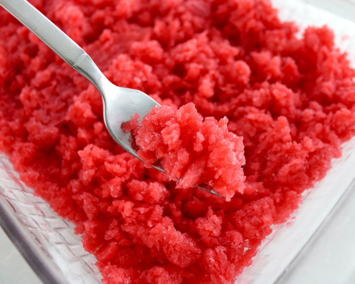fork holding up Raspberry Lemon Granita over glass dish