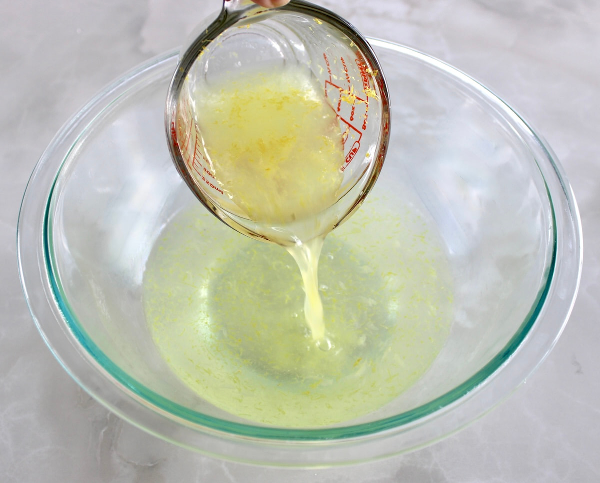 lemon juice and zest pouring into glass bowl with water