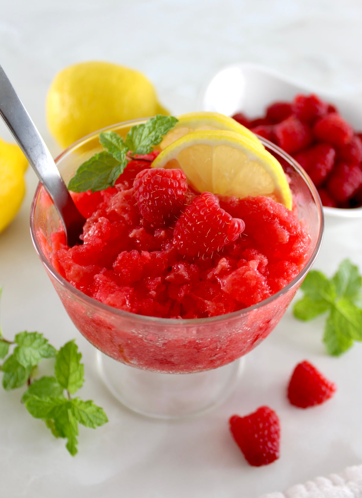 overhead view of Raspberry Lemon Granita with lemon and raspberries