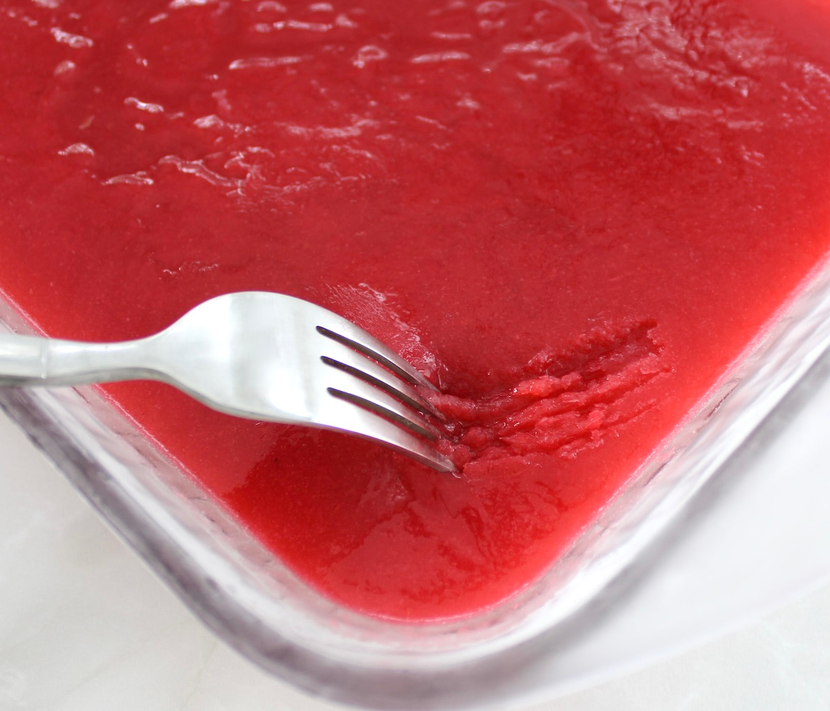 fork scraping Raspberry Lemon Granita in glass dish