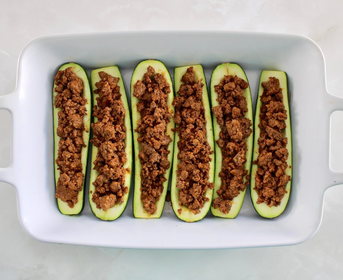 6 zucchini halves in white casserole filled with taco meat