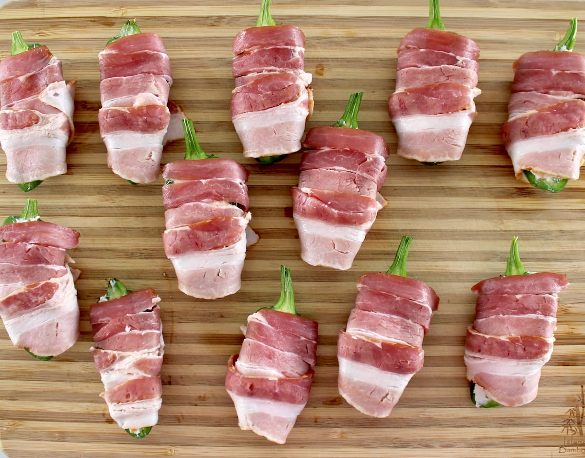 12 unbaked Air Fryer Bacon Wrapped Jalapeño Poppers on cutting board