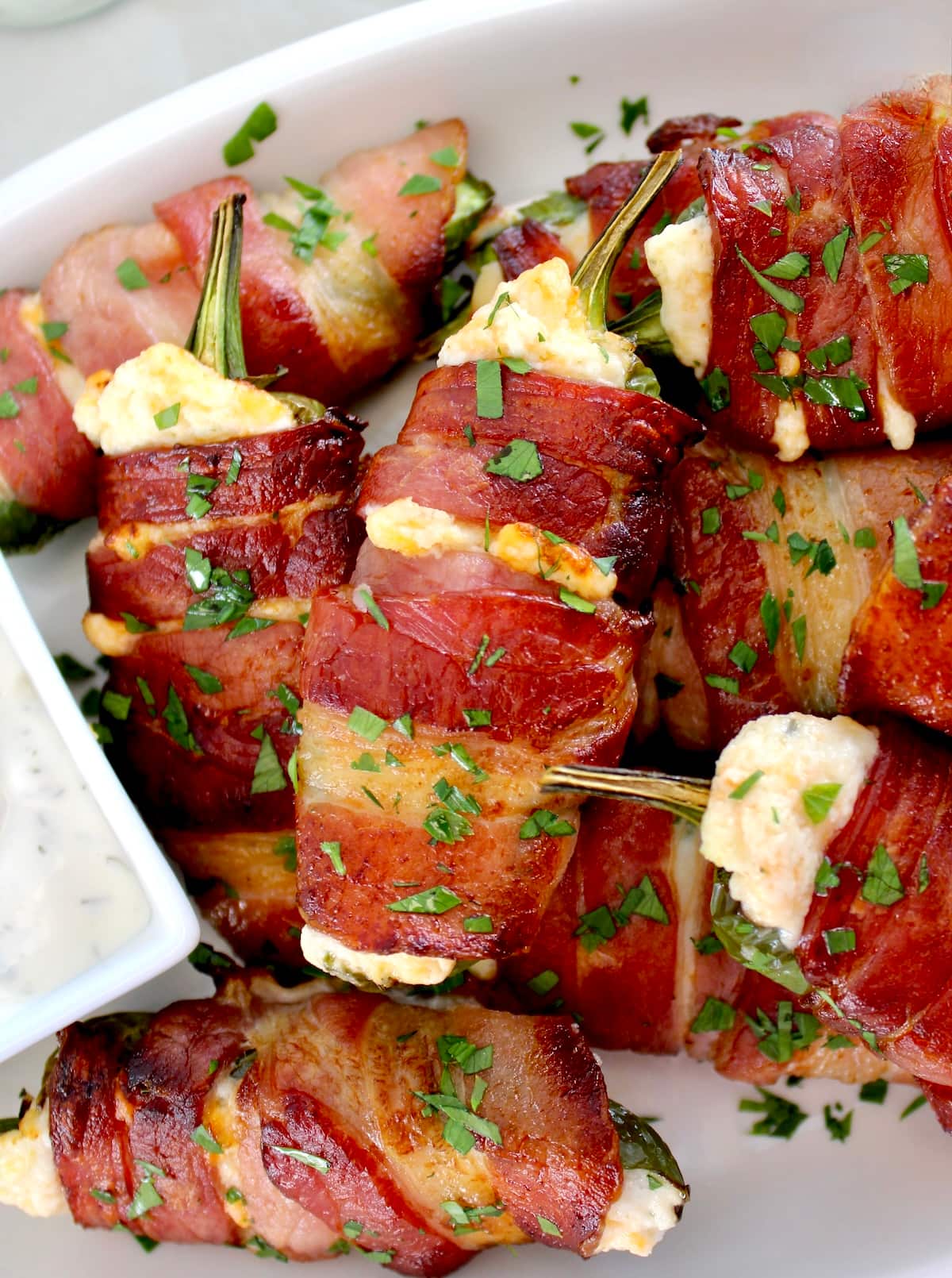 closeup of Air Fryer Bacon Wrapped Jalapeño Poppers on white plate with chopped parsley