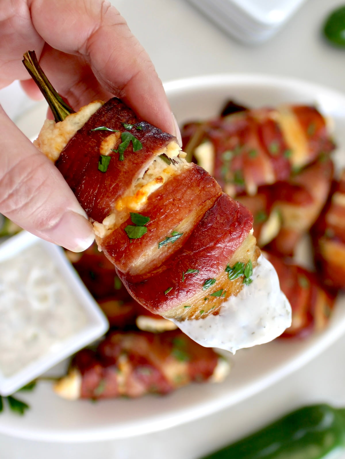 holding up Air Fryer Bacon Wrapped Jalapeño Popper dipped in ranch