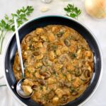 overhead view of Chicken Stroganoff in skillet with silver serving spoon