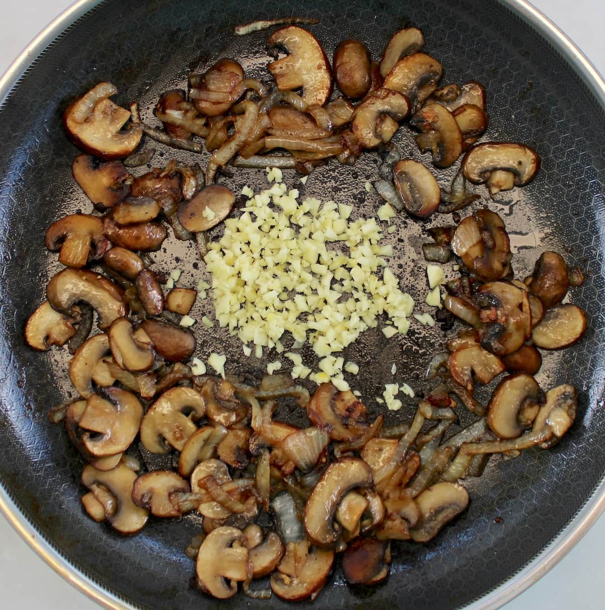 saut&eacute;ed mushrooms and onions in skillet with minced garlic in center