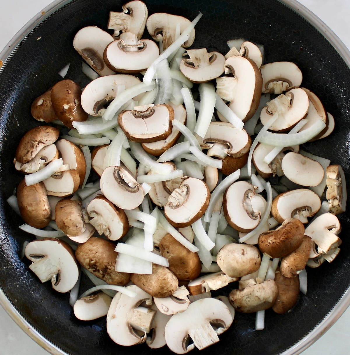 sliced mushrooms and onions raw in skillet