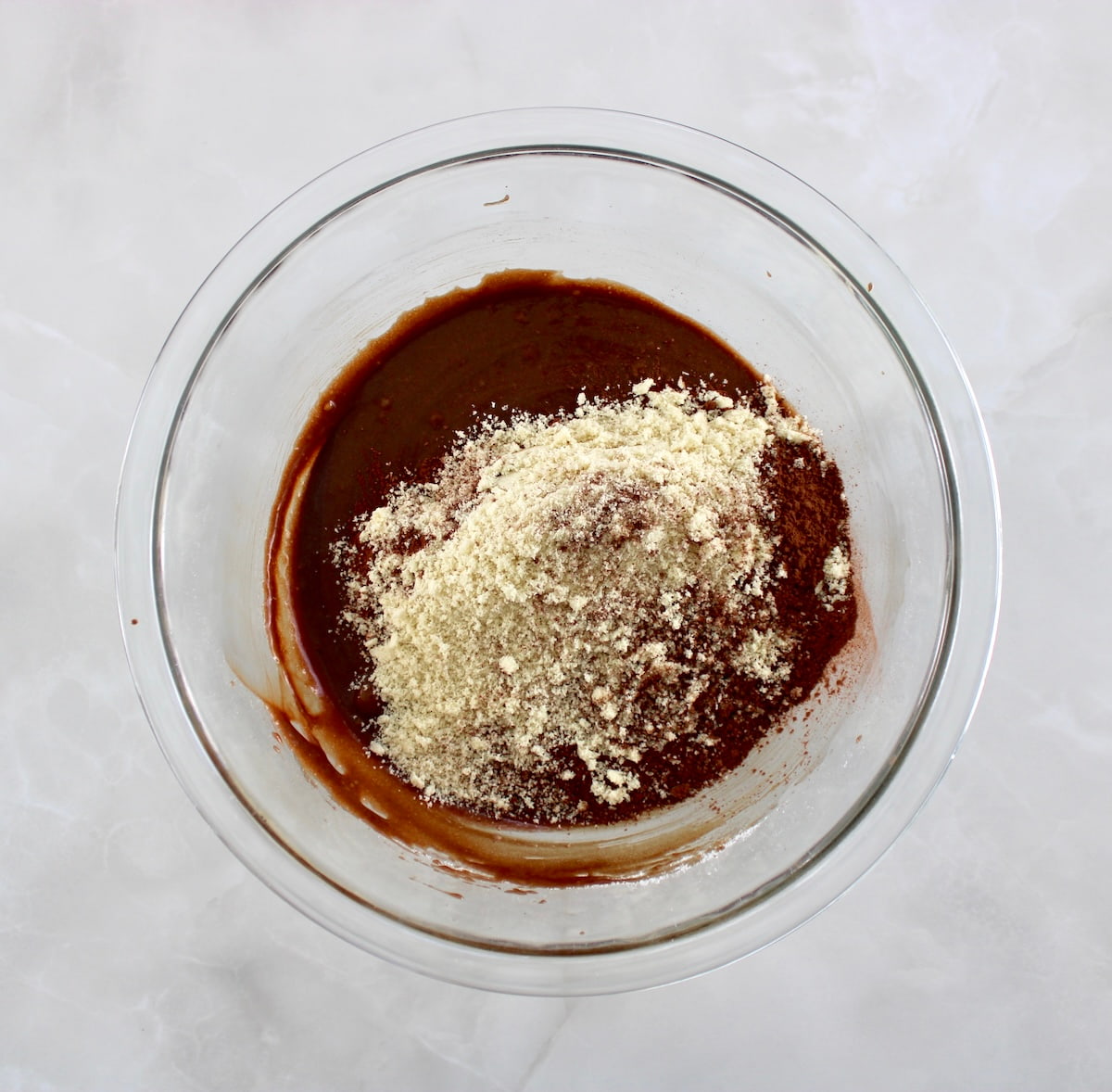 melted chocolate with almond flour and cocoa powder on top unmixed