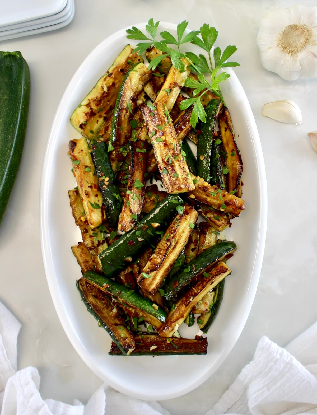 overhead view of Easy Sautéed Zucchini on white oval platter with parsley garnish