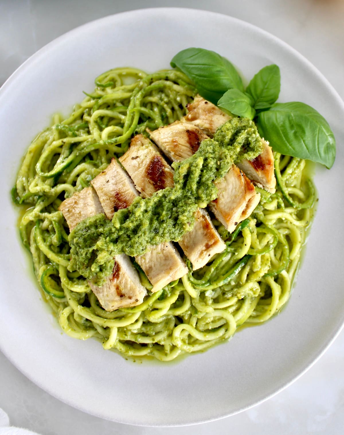 closeup of Grilled Lemon Chicken Pesto Zoodles on white plate