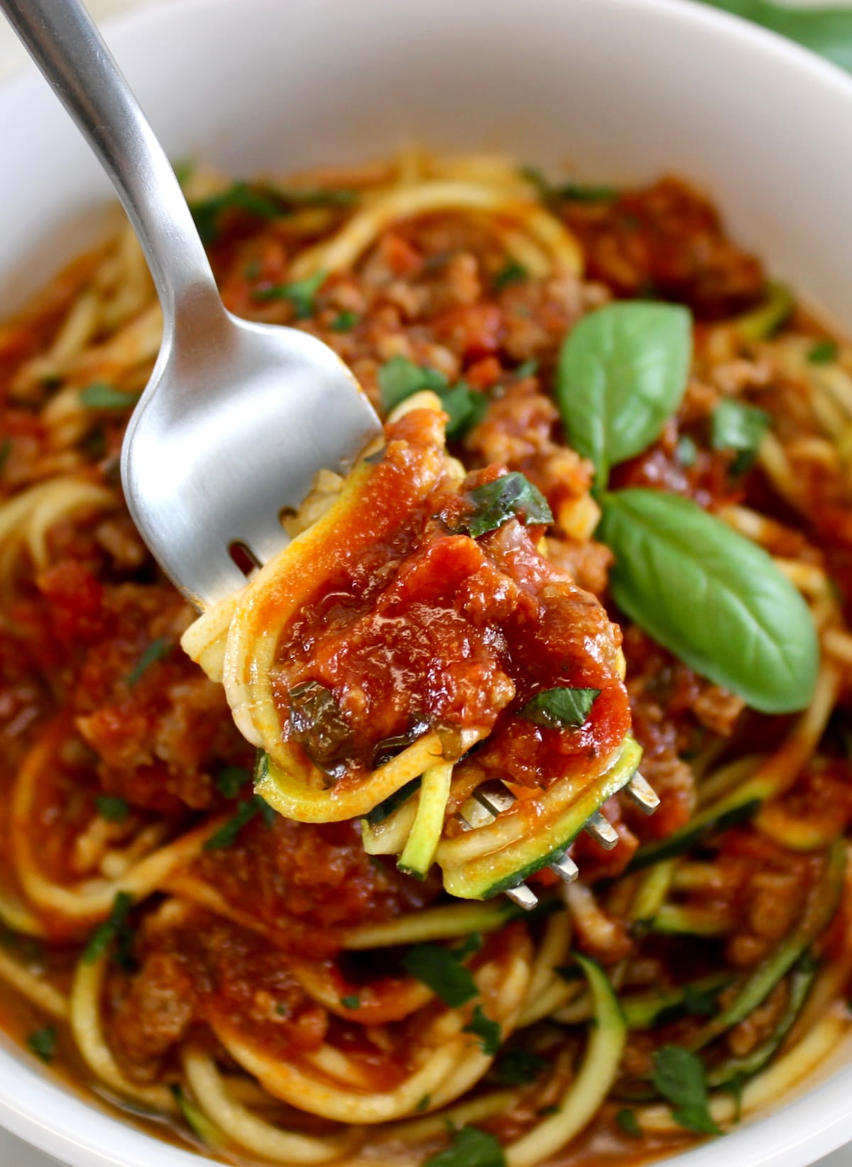 holding up forkful of zucchini noodles with Italian Meat Sauce