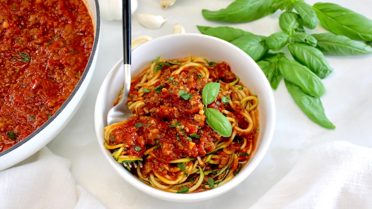 overhead view of zucchini noodles with Italian Meat Sauce and fork in white bowl