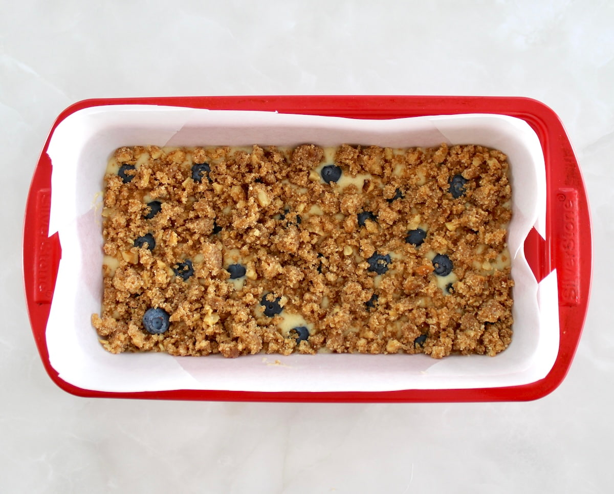 Keto Blueberry Crumb Loaf in red loaf pan with parchment paper unbaked