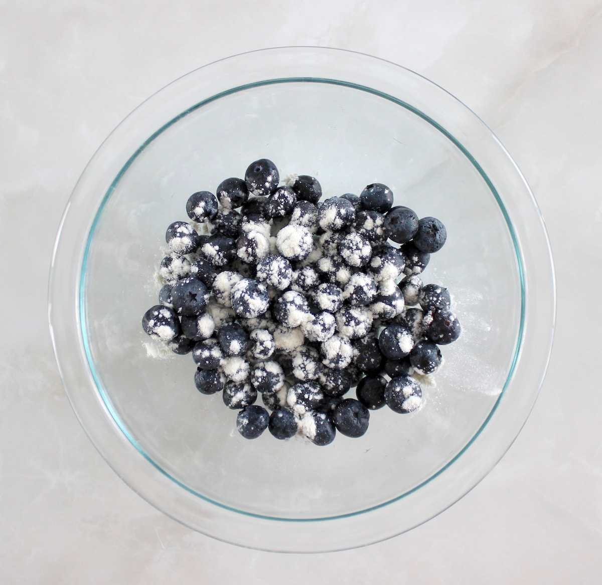 blueberries topped with a dusting of oat fiber in glass bowl