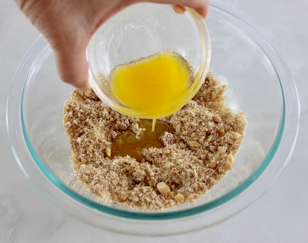 melted poured into Keto Blueberry Crumb topping mixture in glass bowl